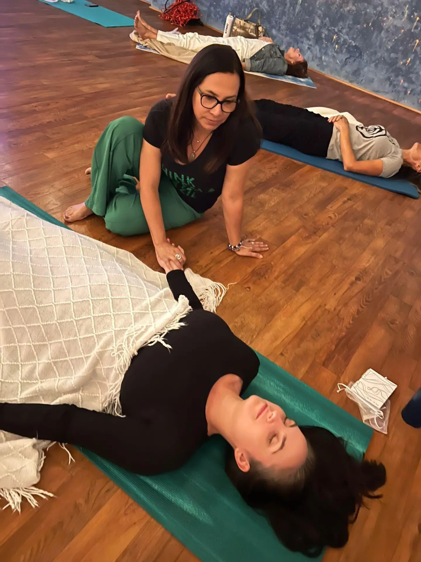 Miria supporting a participant lying on a mat during group breathwork