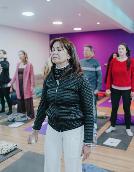Woman standing with eyes closed during a group breathing practice