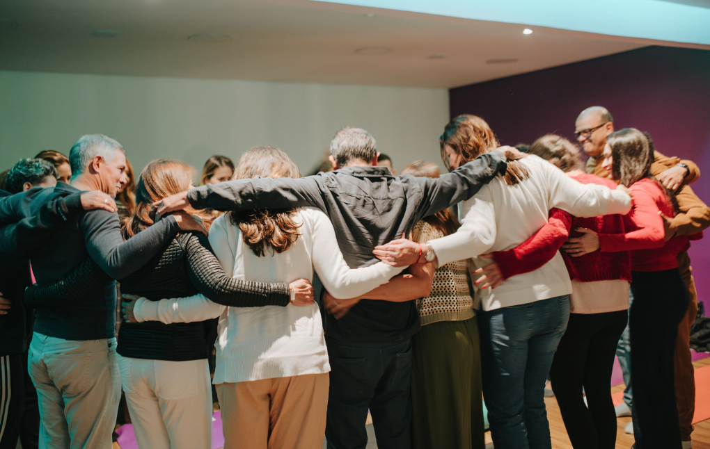 Group standing in a circle with arms around each other